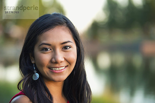 Porträt einer schönen jungen philippinischen Frau  die im Herbst in einem Stadtpark lächelt; St. Albert  Alberta  Kanada'.