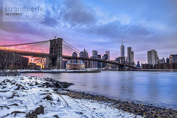 Brooklyn Bridge mit schneebedeckter Landschaft bei Sonnenuntergang  Brooklyn Bridge Park; Brooklyn  New York  Vereinigte Staaten von Amerika'.
