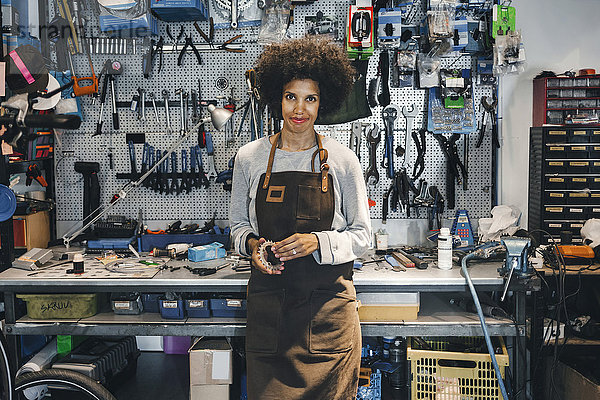 Porträt einer selbstbewussten Mechanikerin mit Fahrradausrüstung in der Werkstatt