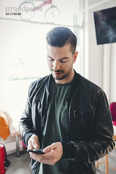 Mittlerer Erwachsener Kunde mit Handy in der Werkstatt