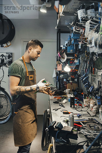 Mittlerer Erwachsener Mechaniker repariert Fahrradpedal in der Werkstatt