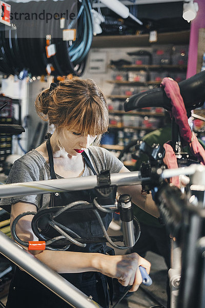 Mittlerer Erwachsener Mechaniker Reparatur Fahrrad in der Werkstatt