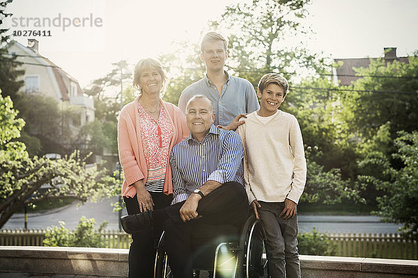 Porträt eines glücklichen behinderten Mannes mit Familie auf dem Hof