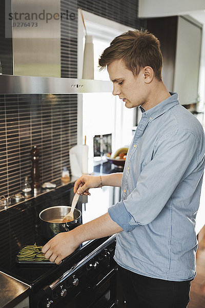 Junger Mann bei der Zubereitung von Speisen in der Küche