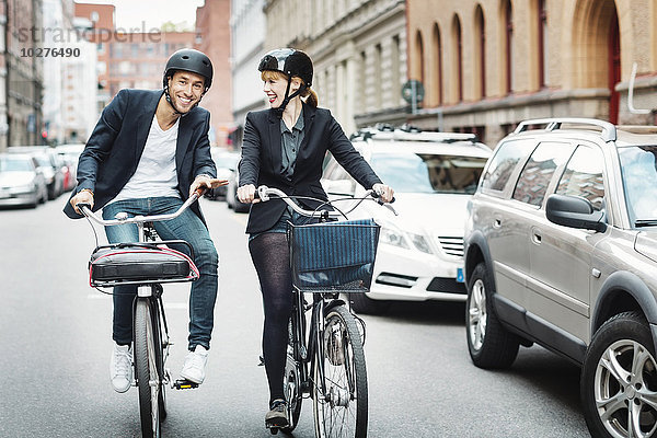 Fröhliche Geschäftsleute mit dem Fahrrad auf der Stadtstraße