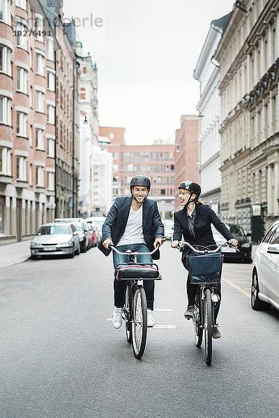 Glückliche Geschäftsleute auf Fahrrädern in der Stadt