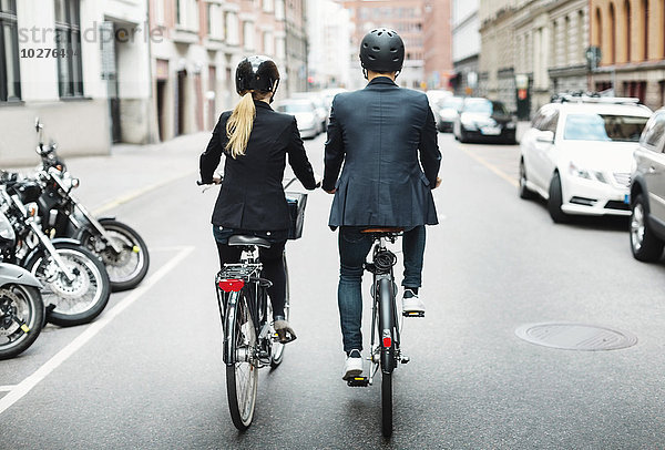 Rückansicht von Geschäftsleuten beim Fahrradfahren auf der Straße