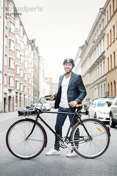 Porträt eines glücklichen Geschäftsmannes mit Fahrrad auf der Stadtstraße