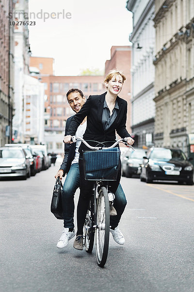 Glückliche Geschäftsleute mit dem Fahrrad auf der Stadtstraße