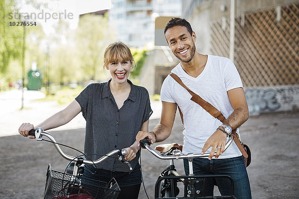 Porträt von glücklichen Geschäftsleuten mit Fahrrädern auf der Stadtstraße