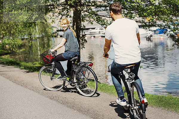 Fröhliche Geschäftsfrau beim Fahrradfahren auf der Straße am See
