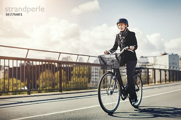 Geschäftsfrau fährt Fahrrad auf der Brücke in der Stadt