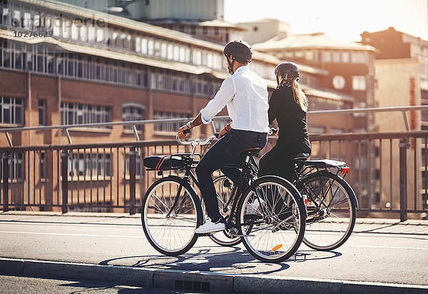 Rückansicht von Geschäftsleuten  die auf der Brücke Fahrrad fahren