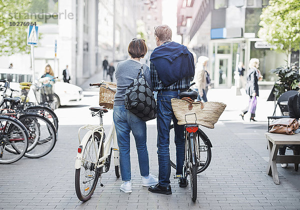 Rückansicht des Seniorenpaares mit Fahrrädern auf der Stadtstraße