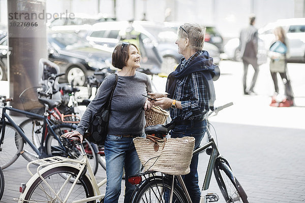 Glückliches Seniorenpaar mit Fahrrädern auf der Stadtstraße