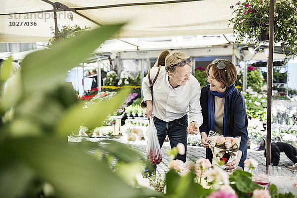 Fröhliches Senior-Paar beim Blumenkauf auf dem Markt