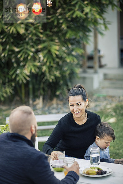 Glückliche Familie beim Abendessen bei Tisch im Hof