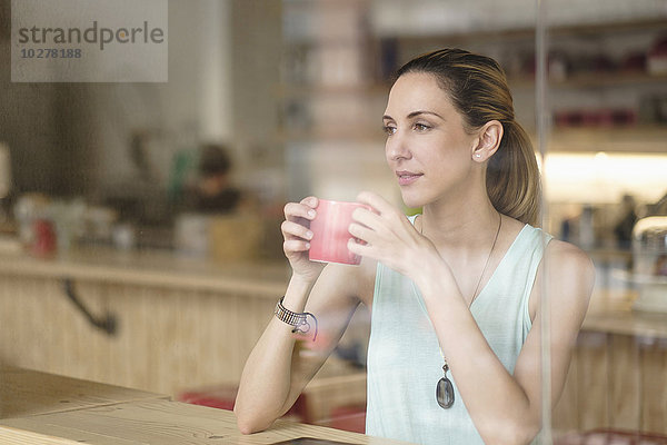 Frau hält Kaffeetasse in einem Cafe