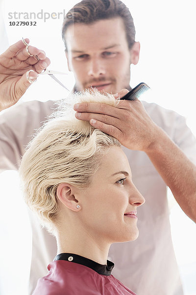 Friseur schneidet einer Frau die Haare