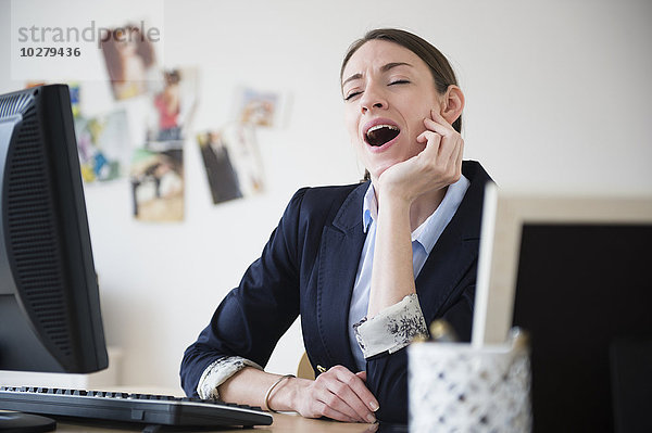 Frau gähnt im Büro