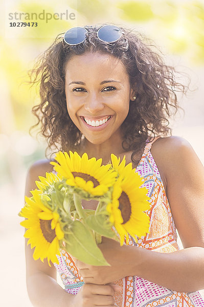 Porträt einer lächelnden Frau mit Sonnenblumen
