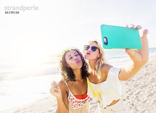 Weibliche Freunde nehmen Selfie am Strand
