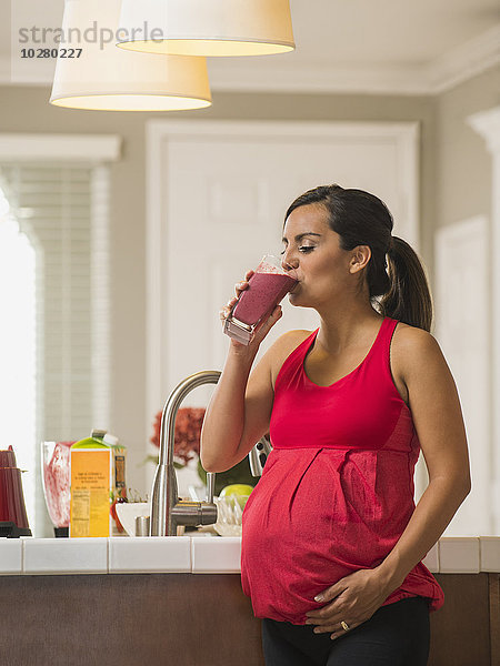 Porträt einer schwangeren Frau  die einen Fruchtcocktail trinkt