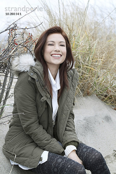 Porträt einer Frau im Parka am Winterstrand