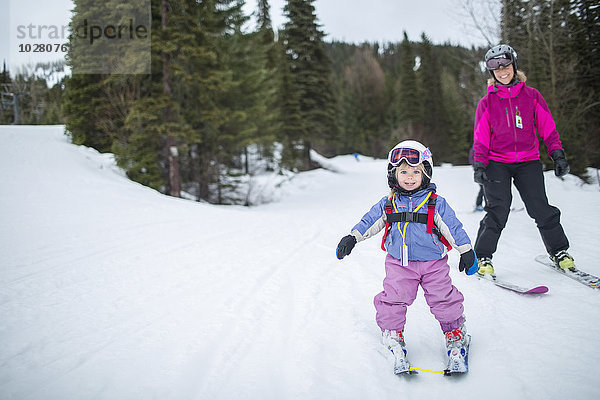 Kleines Mädchen (2-3)  das mit seiner Mutter Skifahren lernt