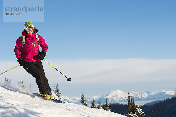 Reife Frau auf Skipiste gegen Himmel