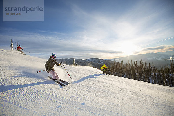 Drei Personen auf der Skipiste bei Sonnenlicht