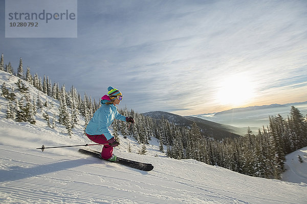 Reife Frau auf Skipiste bei Sonnenuntergang