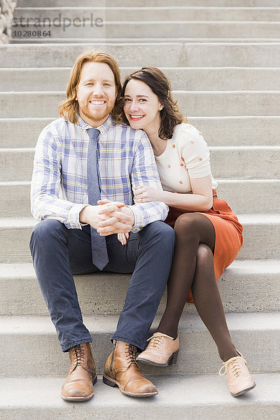 Lächelndes Paar auf Stufen sitzend
