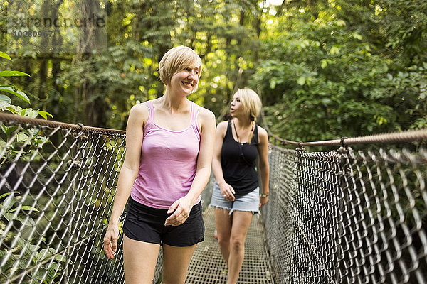 Junge Frauen gehen auf einem Steg im Wald spazieren