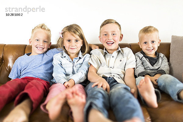 Lächelnde Kinder (2-3  4-5  6-7) auf dem Sofa sitzend