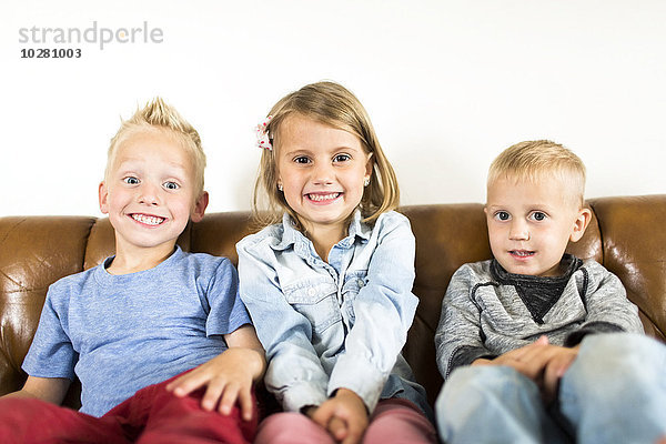 Lächelnde Kinder (2-3  4-5) auf dem Sofa sitzend