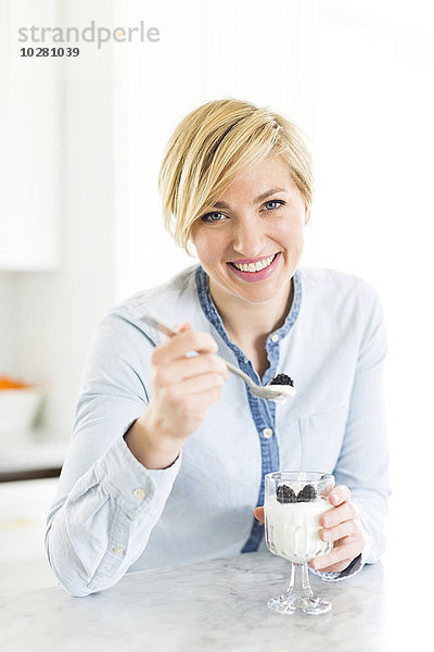 Porträt einer Frau  die Joghurt mit Brombeeren isst