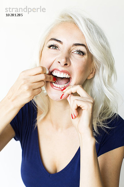 Studioaufnahme einer Frau mit Zahnseide