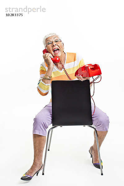 Ältere Frau sitzt auf einem Stuhl und telefoniert