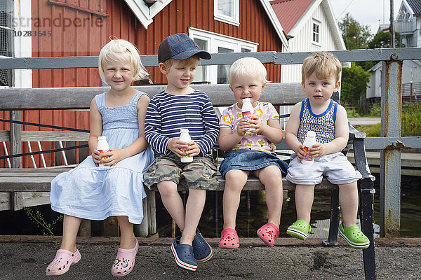 Kinder auf einer Bank beim Trinken