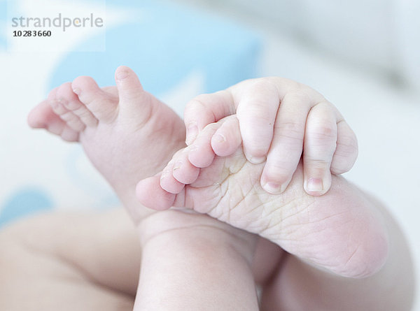 Nahaufnahme von Babyhänden  die Füße halten