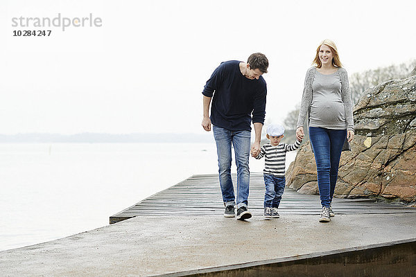 Familie mit Sohn beim Spaziergang auf dem Bootssteg