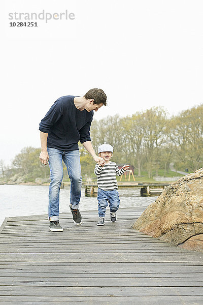 Vater mit Sohn beim Spaziergang auf dem Bootssteg
