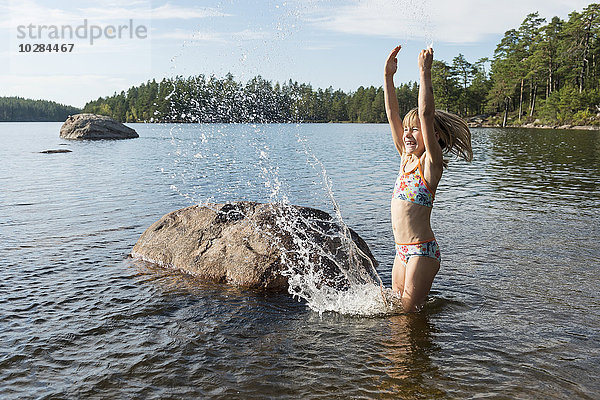 Glückliches Mädchen  das im See Wasser spritzt