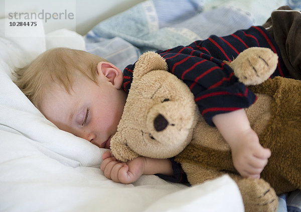Junge schläft mit seinem Teddybär