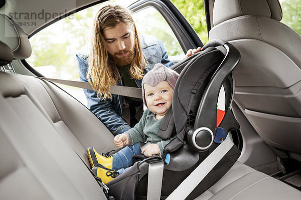 Vater setzt Baby in Autositz