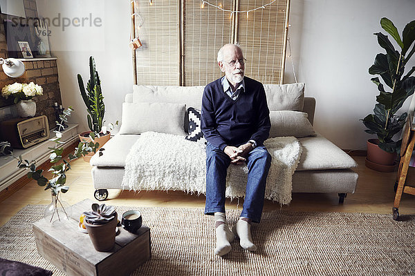 Älterer Mann sitzt im Wohnzimmer