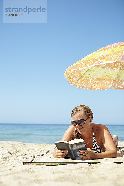 Frau liest Buch am Strand