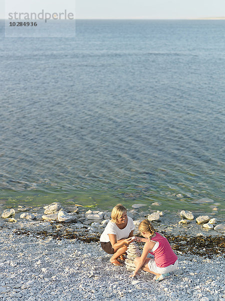 Mutter mit Tochter stapeln Steine am Strand