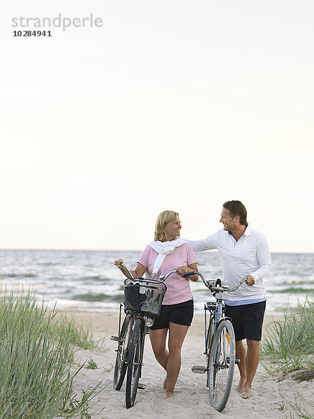 Ehepaar mit Fahrrädern am Strand